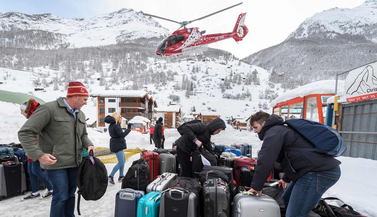 Sejumlah turis merapihkan koper bawaannya setelah dievakuasi dari ski Zermatt di  Taesch, Pegunungan Alpen Swiss (10/1). Bencana tersebut menyebabkan terputusnya jalur kereta api dan seluruh akses menuju Zermatt. (AFP Photo/Fabrice Coffrini)
