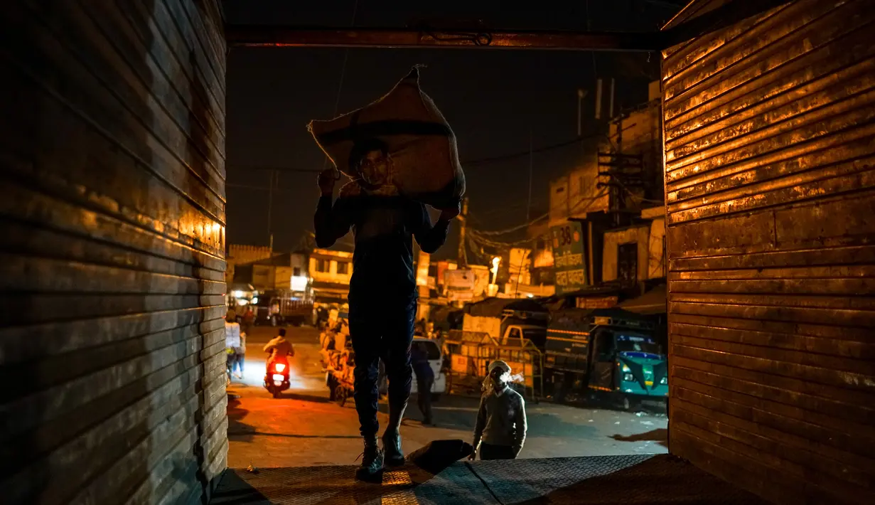 Seorang buruh mengangkat sekarung barang di kawasan tua New Delhi, India (6/3). Karena tuntutan ekonomi para buruh India ini harus rela hidup seadanya, bahkan mereka masih bekerja hingga larut malam. (AFP Photo/Chandan Khanna)