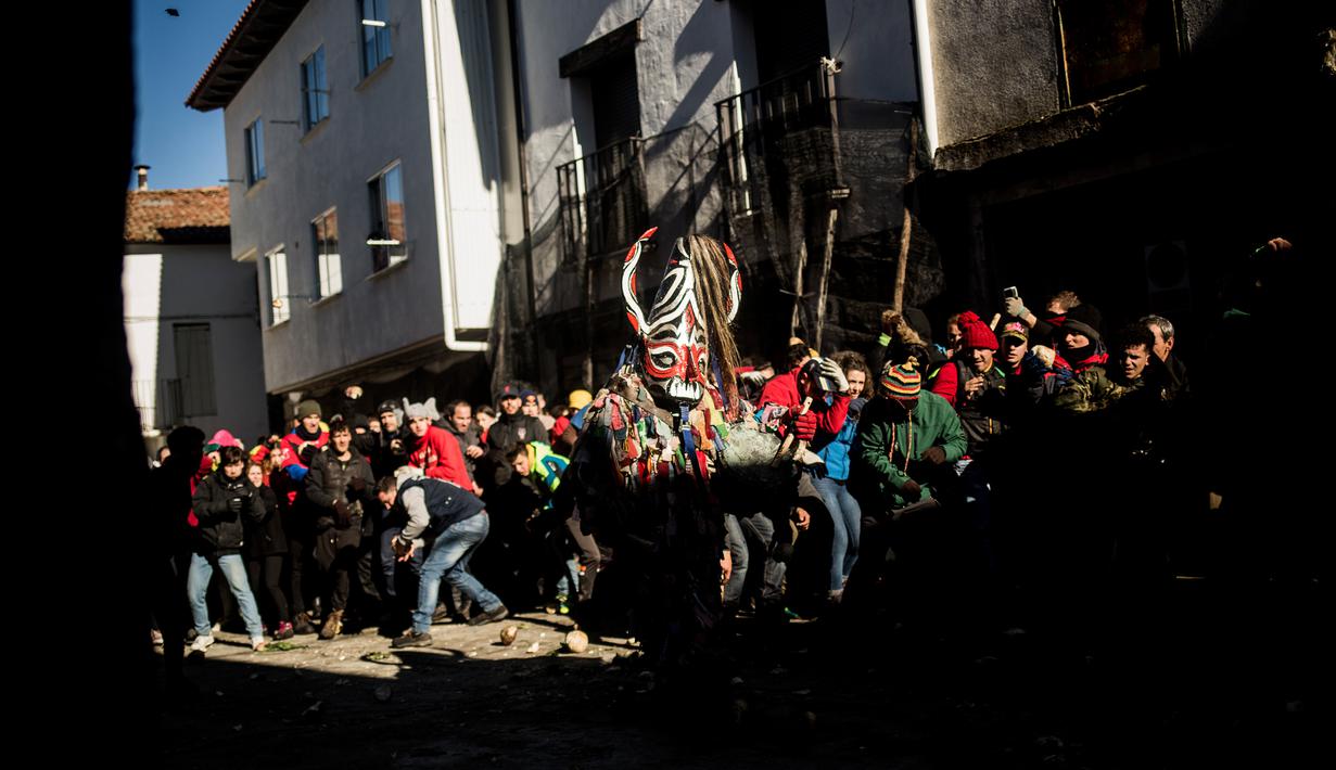Orang-orang melempari seorang pria berkostum ala setan dengan sayuran lobak selama Festival Jarramplas di kota Piornal, Spanyol, Sabtu (19/1). Meski berlangsung selama berabad-abad namun tidak diketahui pasti asal muasal festival ini. (AP/Javier Fergo)