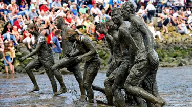 Peserta berjalan meninggalkan lapangan usai bermain bola tangan yang dinamakan "Wattoluempiade" (Olimpiade Lumpur) di Brunsbuettel, Jerman, (30/7). (REUTERS/Fabian Bimmer)