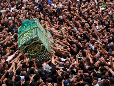 Umat Syiah Irak membawa peti jenazah saat memperingati wafatnya Imam Musa al-Kadhim di Kadhimiya, distrik utara Baghdad, Irak (23/4). Imam Musa al-Kadhim adalah imam ketujuh dari 12 imam Syiah yang meninggal pada 799. (AFP/Sabar Arar)