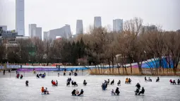 Orang-orang menggunakan kursi yang dimodifikasi untuk meluncur melintasi es dalam kolam saat pekan liburan Tahun Baru Imlek di taman umum selama pekan liburan Tahun Baru Imlek di Beijing, China, Kamis (26/1/2023). (AP Photo/Mark Schiefelbein)