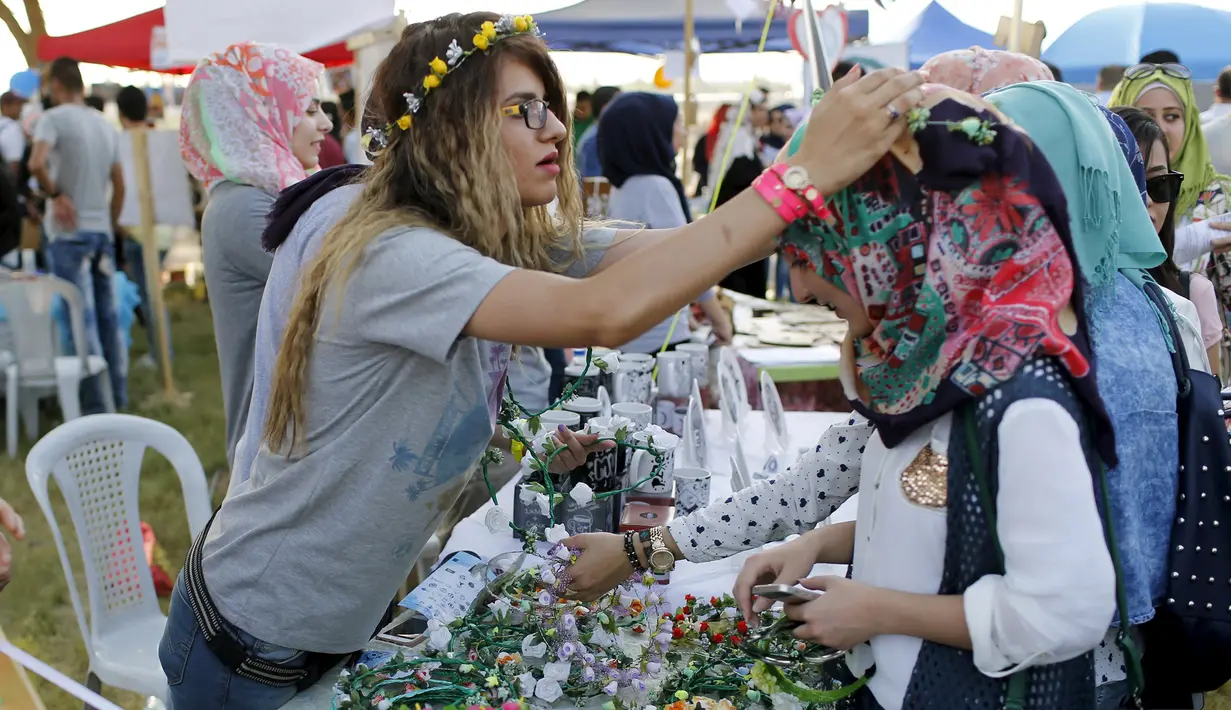 Seorang pengunjung saat dipakaikan hiasan dikepalanya saat mengunjungi festival memperingati Hari Perdamaian Internasional di Baghdad, Irak (21/9/2015). Perayaan diisi dengan kreativitas seni karya para pemuda dan pemudi Irak. (REUTERS/Thaier al-Sudani)