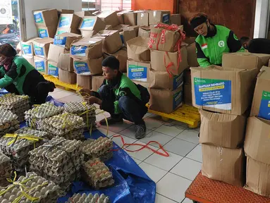 Pengemudi ojek online mengemas bansos untuk warga yang terdampak COVID-19 di Kantor Pos, Cibinong, Bogor, Jawa Barat, Senin (20/4/2020). Pemprov Jabar menyalurkan bansos senilai Rp 500 ribu bagi warga berpenghasilan rendah dan termasuk miskin baru akibat pandemi COVID-19. (merdeka.com/Arie Basuki)