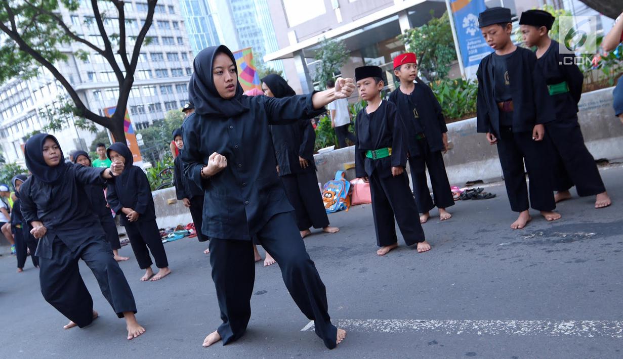 Sejumlah pendekar perempuan memperagakan jurus beladiri di hadapan warga saat Car Free Day di kawasan Senayan, Jakarta, Minggu (8/10). Aksi ini untuk melestarikan olahraga pencak silat Betawi. (Liputan6.com/Fery Pradolo)