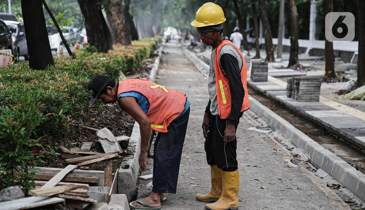Pekerja menyelesaikan proyek revitalisasi pedestrian di kawasan Jalan Pattimura, Jakarta, Rabu (8/6/2022). Dinas Bina Marga DKI Jakarta merevitalisasi pedestrian dengan memperlebar menjadi tiga meter sehingga cukup luas untuk memberikan kenyamanan para pejalan kaki. (Liputan6.com/Faizal Fanani)