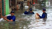 Petugas Sudin Sumber Daya Air (SDA) memunguti sampah-sampah yang tergenang saat banjir di kawasan Kampung Melayu Kecil, Bukit Duri, Jakarta, Selasa (25/2/2020). Banjir tersebut akibat luapan sungai Ciliwung. (merdeka.com/magang/ Muhammad Fayyadh)