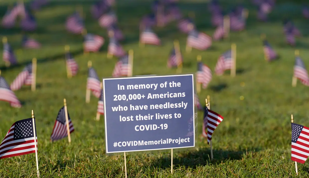 Aktivis dari COVID Memorial Project meletakkan ribuan bendera Amerika berukuran kecil di di halaman National Mall di Washington, Selasa (22/9/2020). Ribuan bendera itu menandai 200 ribu nyawa yang hilang akibat virus corona Covid-19 di Amerika Serikat. (AP Photo/J. Scott Applewhite)