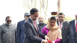 Presiden Joko Widodo dan Ibu Negara Iriana Joko Widodo menyiramkan air ke pohon Tanjung saat mengunjungi National Martyrs’ Memorial di Savar, Bangladesh (28/1). (Liputan6.com/Pool/Rusman Biro Pers Setpres)