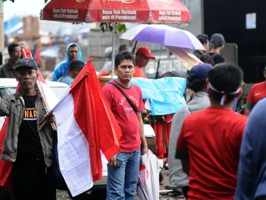 Pedagang menawarkan bendera kepada suporter Timnas Indonesia di sekitar Stadion Pakansari, Bogor, Sabtu (3/12). Timnas Indonesia akan melakoni laga semifinal pertama Piala AFF 2016 melawan Vietnam. (Liputan6.com/Helmi Fithriansyah)