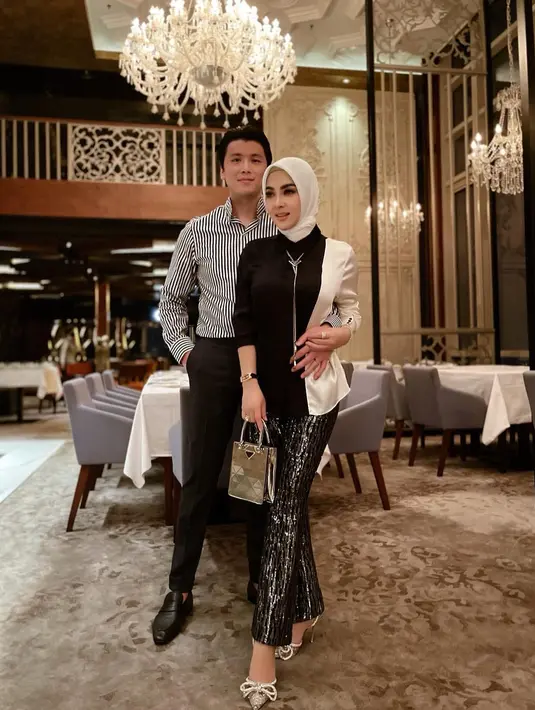 Tampil serasi dan glamor dalam balutan busana nuansa monokrom. Syahrini memadukan two-tone blazer monokrom, celana panjang berkilau, dan tas Prada. Sementara Reino mengenakan striped shirt yang dipadu celana panjang hitam. @princessyahrini.