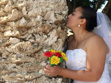 Seorang aktivis lingkungan berpakaian pengantin mencium sebuah pohon di San Jacinto Amilpas, Oaxaca, Meksiko, Minggu (25/2). Acara ini bernama "Menikah dengan Pohon". (AFP FOTO/PATRIKIA CASTELLANOS)