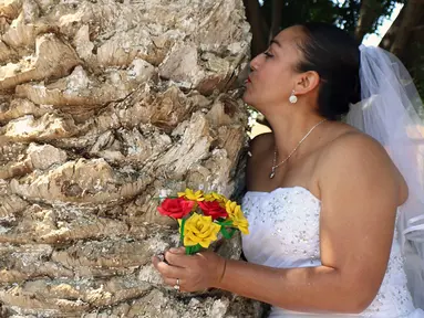 Seorang aktivis lingkungan berpakaian pengantin mencium sebuah pohon di San Jacinto Amilpas, Oaxaca, Meksiko, Minggu (25/2). Acara ini bernama "Menikah dengan Pohon". (AFP FOTO/PATRIKIA CASTELLANOS)