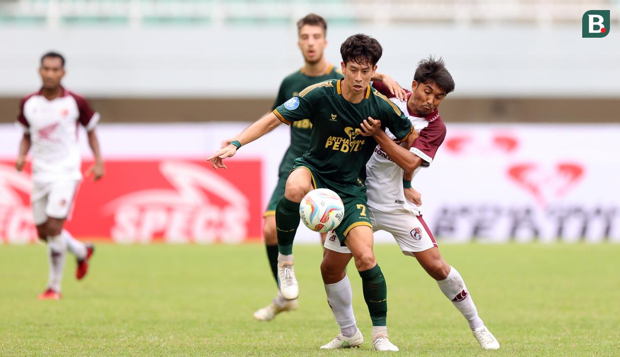 Pemain PSM Makassar, Arfan (kanan), mengawal pergerekan dari pemain Persikabo 1973, Kaishu Yamazaki (tengah), dalam pertandingan lanjutan pekan ketiga BRI Liga 1 2023/2024 yang berlangsung di Stadion Pakansari, Cibonong, Jawa Barat, Jumat (14/7/2023). (Bola.com/Abdul Aziz)