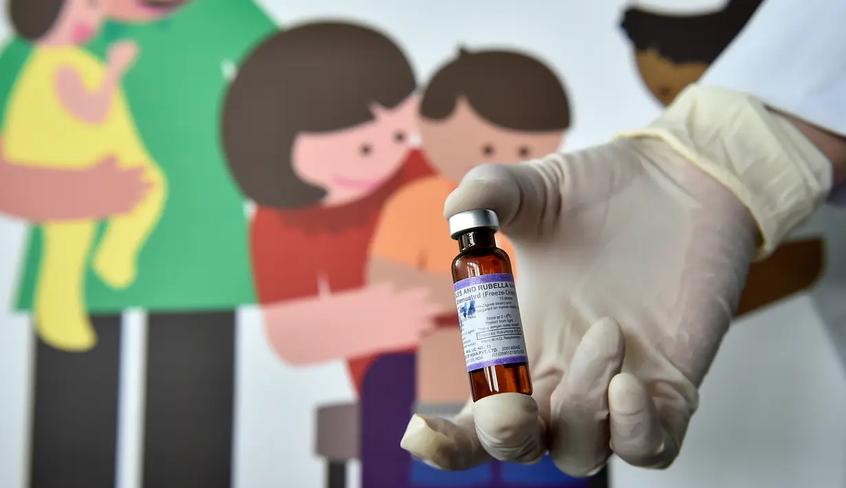 Petugas menunjukan Vaksin Campak dan Rubella (MR) sebelum melakukan imuniasasi kepada anak di sebuah puskesmas, Banda Aceh, Rabu (19/9). Saat ini hanya tujuh persen anak dari target 1,5 juta orang di Aceh yang telah diimunisasi. (CHAIDEER MAHYUDDIN / AFP)