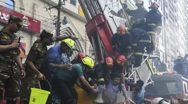 Petugas pemadam kebakaran Bangladesh menyelamatkan seorang pria dari gedung kantor yang terbakar di Dhaka (28/3). Kebakaran besar melanda gedung perkantoran yang menewaskan sedikitnya lima orang dan lainnya masih terperangkap dalam gedung yang terbakar tersebut. (AFP/Munir Uzzaman)