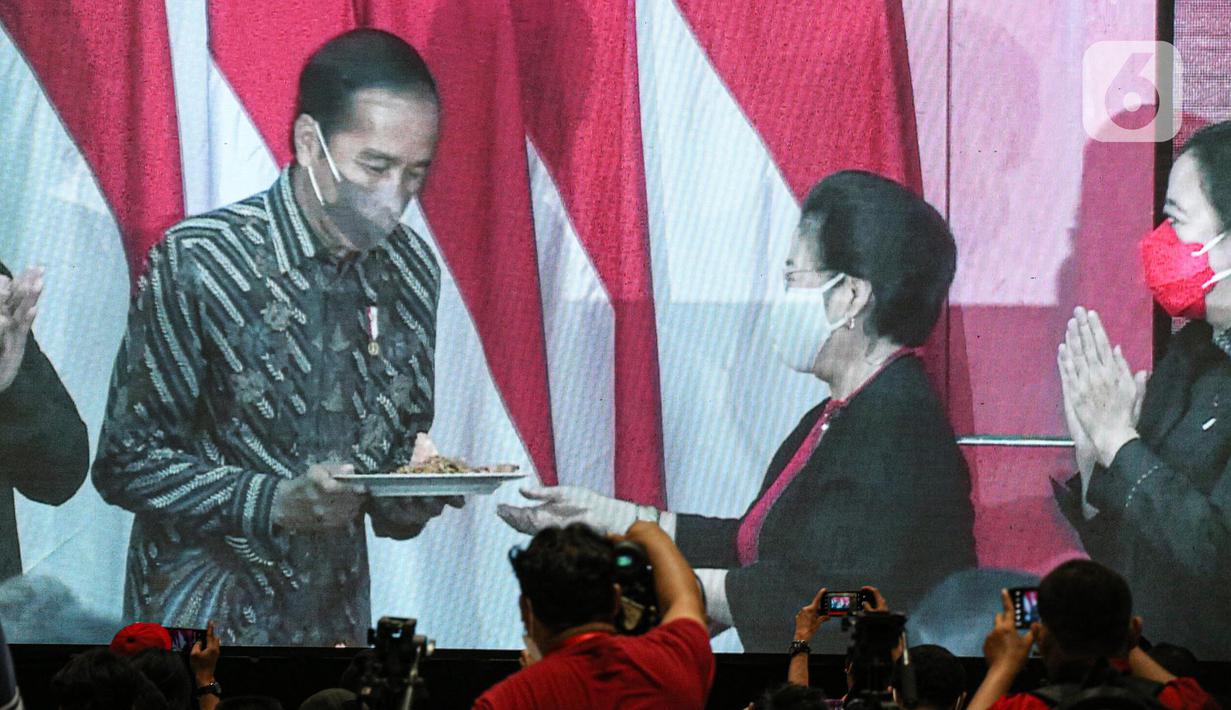 Presiden Joko Widodo atau Jokowi (kiri) memberikan tumpeng kepada Ketua Umum PDIP Megawati Soekarnoputri (kedua kanan) saat Rakernas II PDIP di Jakarta, Selasa (21/6/2022). Rakernas PDIP kali ini mengusung tema 'Desa Kuat, Indonesia Maju dan Berdaulat'. (Liputan6.com/Faizal Fanani)