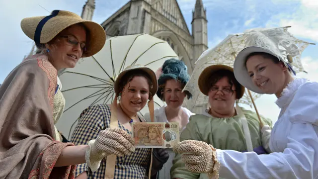 Orang-orang mengenakan kostum masa lampau berpose dengan uang kertas sepuluh pound baru Bank of England, yang menampilkan penulis Jane Austen, selama peluncurannya di Katedral Winchester di Winchester, Inggris selatan, pada tanggal 18 Juli 2017.