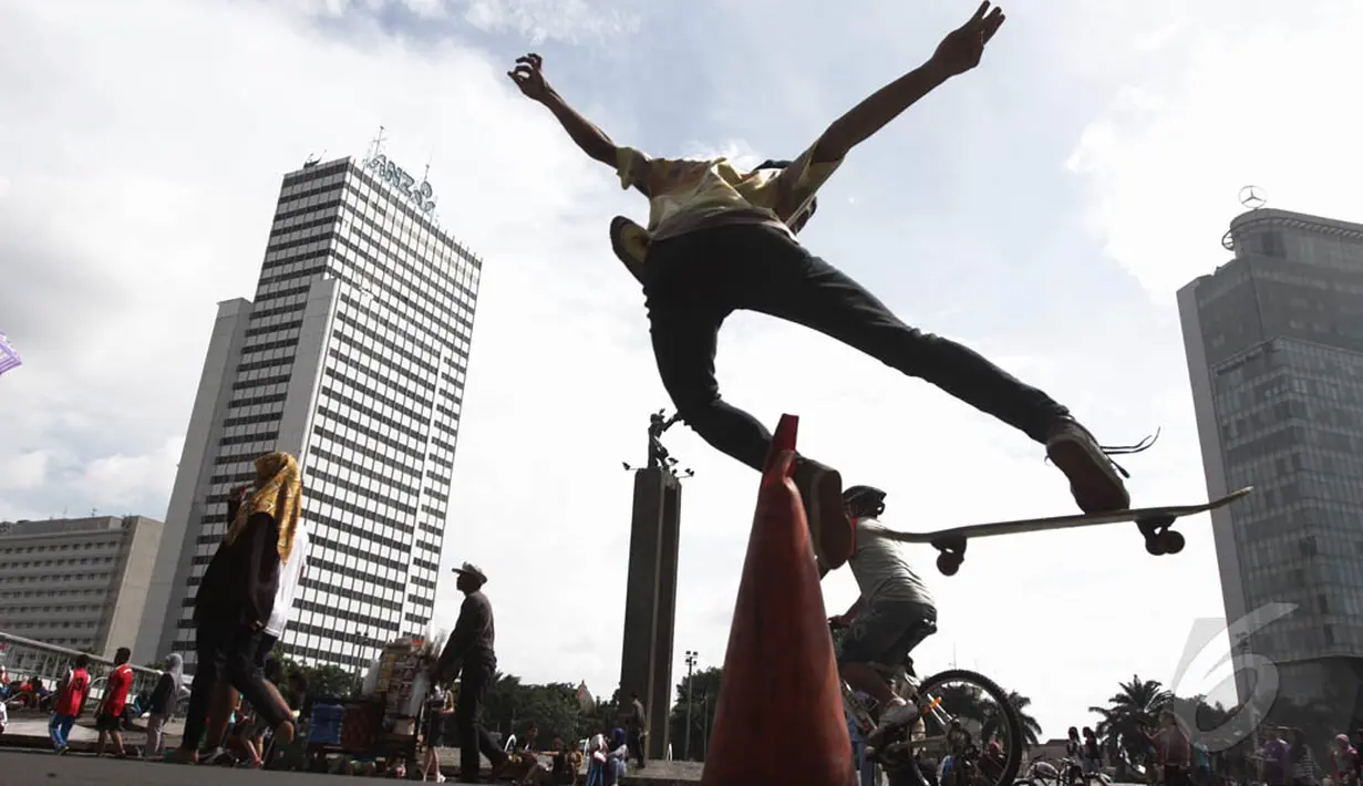 Seorang remaja beraksi dengan skateboard-nya saat hari bebas kendaraan (car free day) di kawasan Bundaran HI Jakarta, Minggu (14/12/2015). (Liputan6.com/Faizal Fanani)