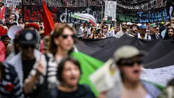 Mereka kembali berunjuk rasa mendesak penghentian serangan militer Israel di wilayah Gaza. Tampak dalam foto, para demonstran pro-Palestina membawa bendera, spanduk, dan plakat saat mereka berbaris berunjuk rasa di jalanan kota Sydney, Australia, Minggu 22 Februari 2026. (DAVID GRAY/AFP)