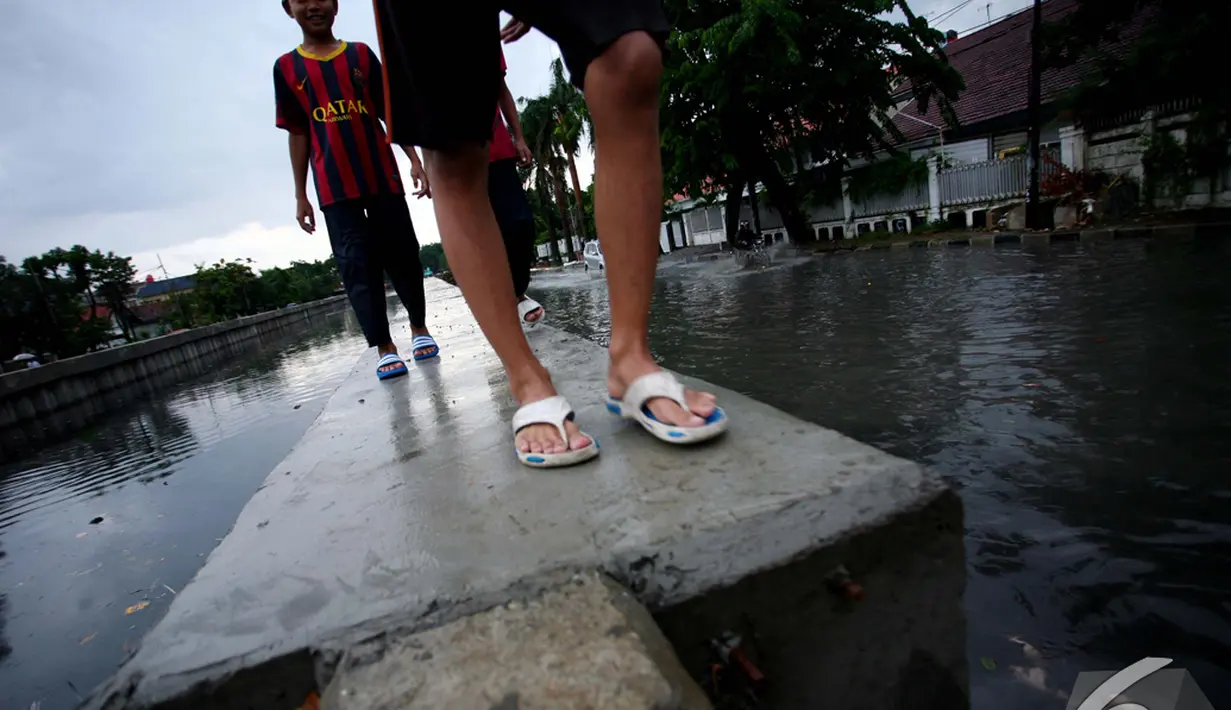 Sejumlah bocah bermain di pinggir Kali Anak Ciliwung yang sedang meluap, Jakarta Pusat, Jumat (5/12/2014). (Liputan6.com/Johan Tallo)
