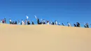 Peserta menghadiri kelas yoga yang diselenggarakan oleh komunitas YSYoga System di gurun Samalayuca, negara bagian Chihuahua, Meksiko pada 25 Mei 2019. Ratusan penggemar yoga mengikuti latihan bersama di bawah terik matahari dan beralaskan pasir. (Herika MARTINEZ/AFP)