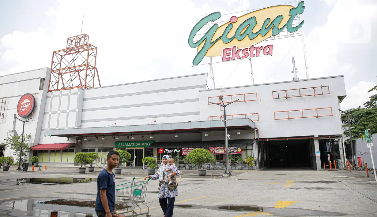 Pengunjung melintas di depan Supermarket Giant Ekstra di Kreo, Tangerang, Senin (2/8/2021). PT Hero Supermarket Tbk resmi menutup seluruh gerai Giant di Indonesia pada Minggu (1/8/2021), dan akan lebih fokus pada pengembangan gerai merek lainnya. (Liputam6.com/Faizal Fanani)