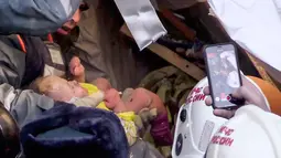 Tim penyelamat mengevakuasi seorang bayi dari reruntuhan puing-puing gedung apartemen yang ambruk di Magnitogorsk, Rusia, Selasa (1/1). Bayi itu ditemukan ketika seorang penolong mendengarnya menangis. (Russian Ministry for Emergency Situations via AP)