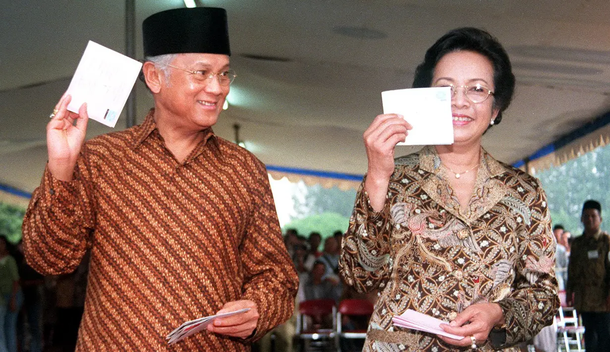 Presiden BJ Habibie didampingi istrinya Ainun Habibie menunjukkan surat suara sebelum melakukan pencoblosan dalam pemilu di Jakarta, 7 Juni 1999. Makam Habibie bakal bersebelahan dengan sang istri tercinta, Ainun Habibie. (AFP Photo/Agus Lolong)