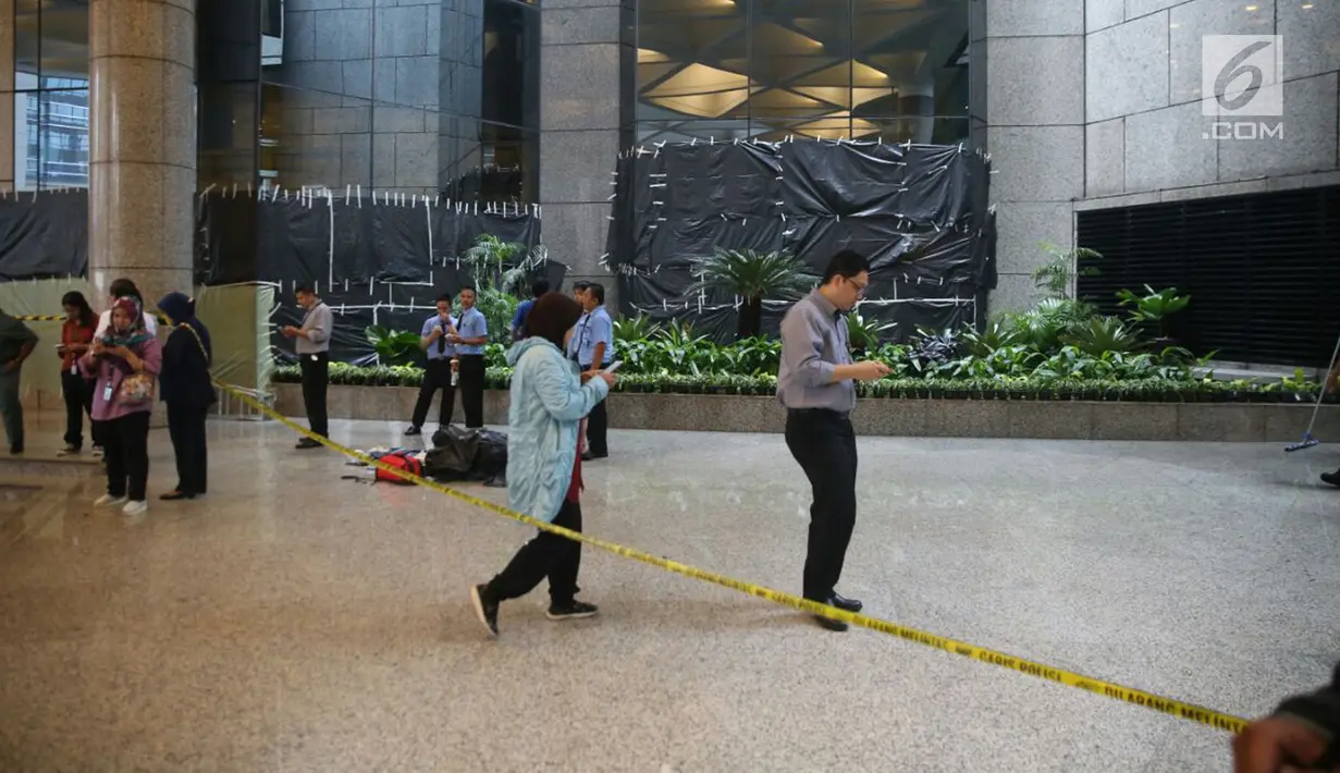 Sejumlah orang berjalan dekat garis polisi yang dipasang setelah ambruknya Selasar Tower II Gedung Bursa Efek Indonesia (BEI), Jakarta, Senin (15/1). Polisi pun mengerahkan tiga anjing pelacak ke lokasi ambruknya balkon BEI. (Liputan6.com/Johan Tallo)