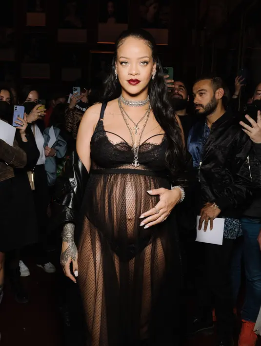 Rihanna kembali tampil memukau dengan koleksi dari Dior Pre Fall. Mengenakan gabardine coat dari katun ringan berwarna hitam, yang dipadunya dnegan fishnet dress yang juga berwarna hitam, Rihanna memamerkan baby bumpnya. Foto: Document/Dior.