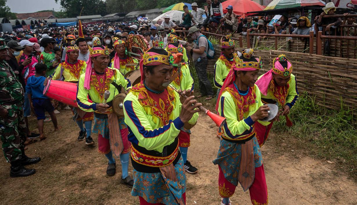 Orang-orang memainkan alat musik saat mereka mengambil banteng untuk parade selama kompetisi balap banteng Karapan Sapi di Bangkalan, pulau Madura, Jawa Timur, Minggu (16/10/2022). Lomba karapan sapi yang memperebutkan Piala Presiden itu diikuti 24 pasang sapi dari sejumlah daerah di Madura. (Juni Kriswanto/AFP)