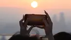 Orang-orang mengambil gambar matahari terbenam terakhir tahun ini di dek observasi menara Namsan di Seoul, Korea Selatan, Minggu (31/12/2023). (Jung Yeon-je / AFP)