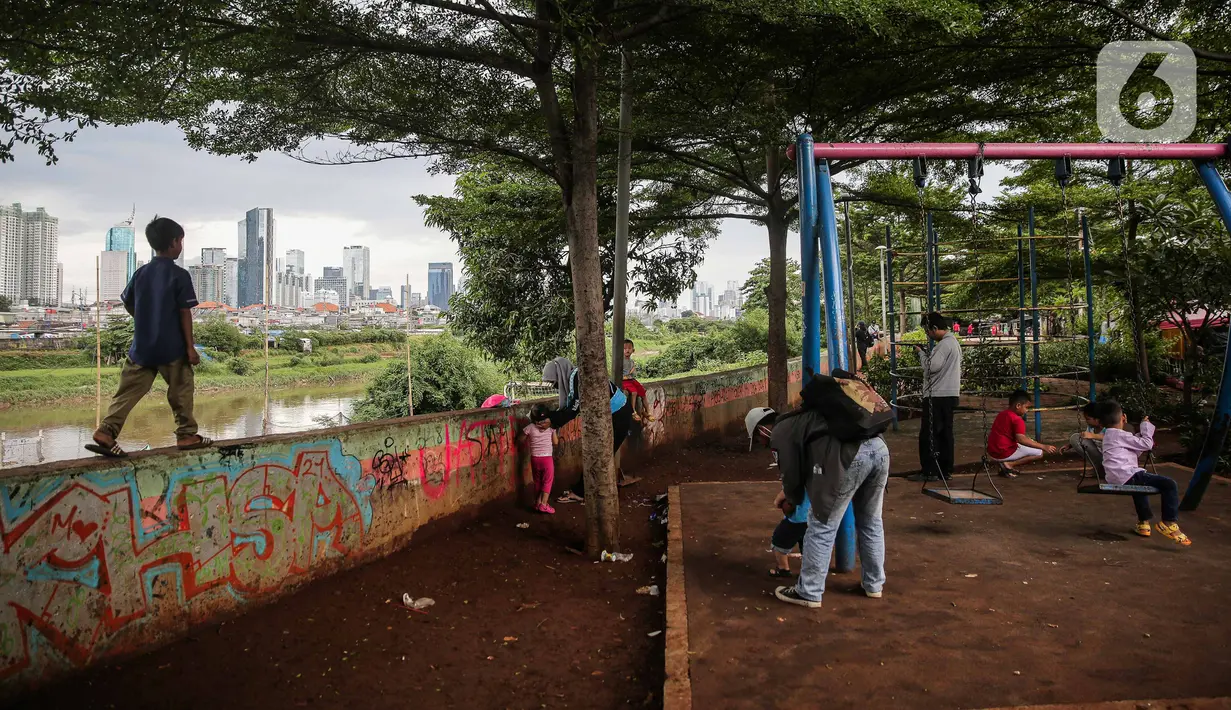 Sejumlah anak bermain di taman bermain yang terdapat di Bantaran Banjir Kanal Barat Kawasan Petamburan, Jakarta, Minggu (12/12/2021). Minimnya taman bermain di pemukiman padat penduduk membuat anak-anak seringkali bermain di tempat yang tidak semestinya. (Liputan6.com/Faizal Fanani)