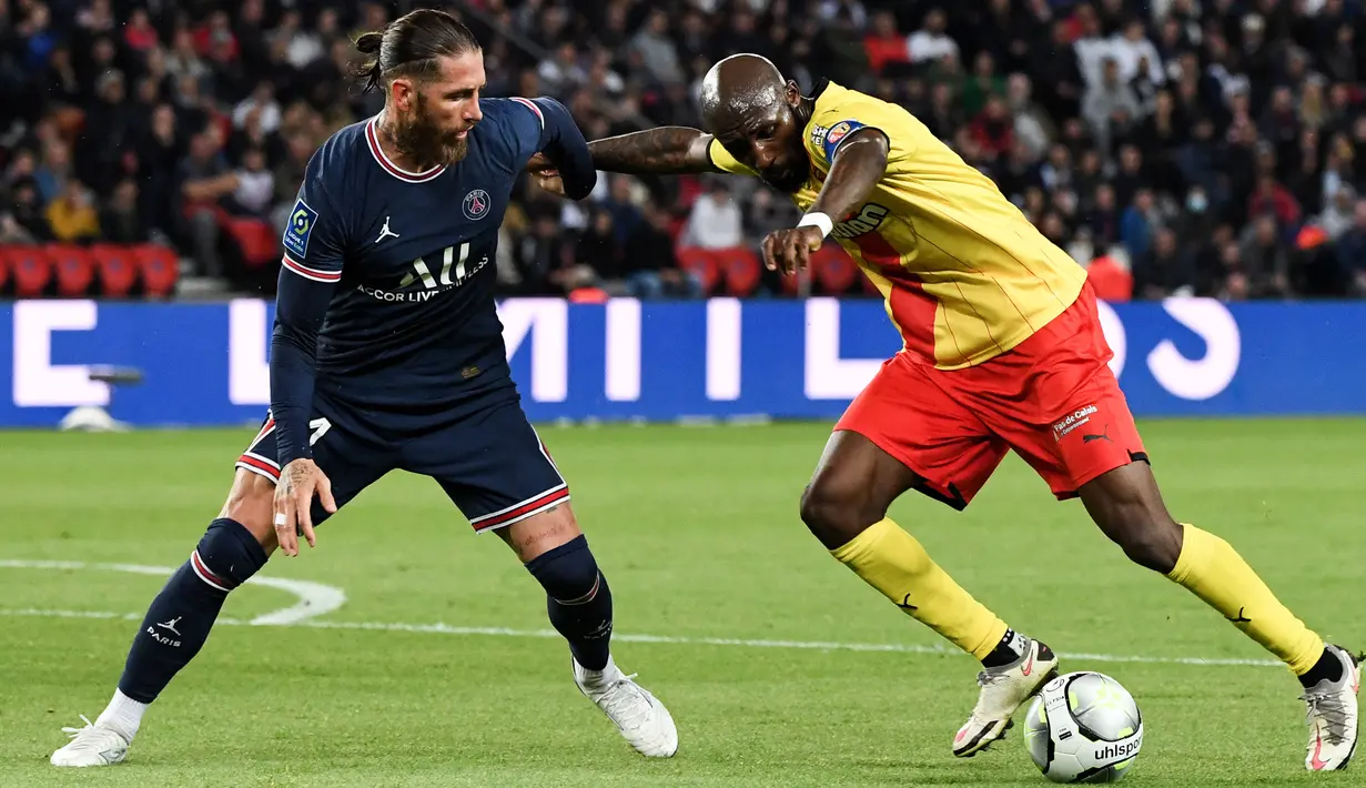 <p>Bek Paris Saint-Germain (PSG) Sergio Ramos (kiri) berebut bola dengan gelandang Lens Seko Fofana dalam pekan ke-34 Ligue 1 di Parc des Princes, Minggu (24/4/2022) dini hari WIB. PSG sudah memastikan gelar juara Ligue 1 Prancis berkat hasil imbang 1-1 dengan tamunya Lens. (Alain JOCARD / AFP)</p>