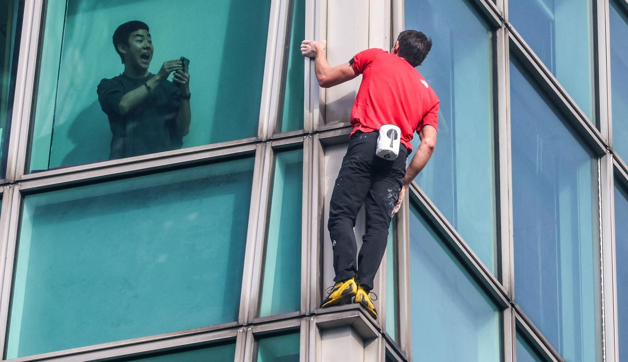 Seorang penghuni gedung merekam aksi atlet panjat tebing 'free solo' asal Amerika, Alex Honnold saat memanjat gedung Taipei 101 tanpa tali pengaman di Taipei, Minggu (25/01/2026). (AFP/I-Hwa Cheng)
