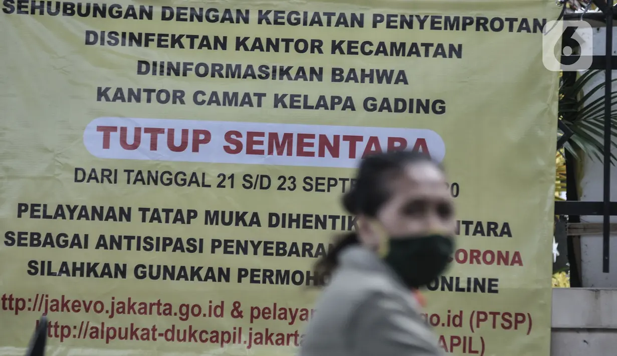 Warga melintas di depan spanduk info penutupan sementara Kantor Kecamatan Kelapa Gading, Jakarta, Senin (21/9/2020). Kantor Kecamatan Kelapa Gading ditutup sementara selama 3 hari hingga Rabu (23/9), pasca meninggalnya Camat Kelapa Gading, M Harmawan akibat COVID-19. (merdeka.com/Iqbal Nugroho)