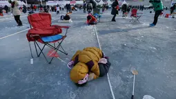 Peserta mengintip keadaan di bawah sungai saat acara Festival Es di sungai Hwacheon yang membeku di Korea Selatan, Sabtu (14/1). (AP Photo/Ahn Young-joon)