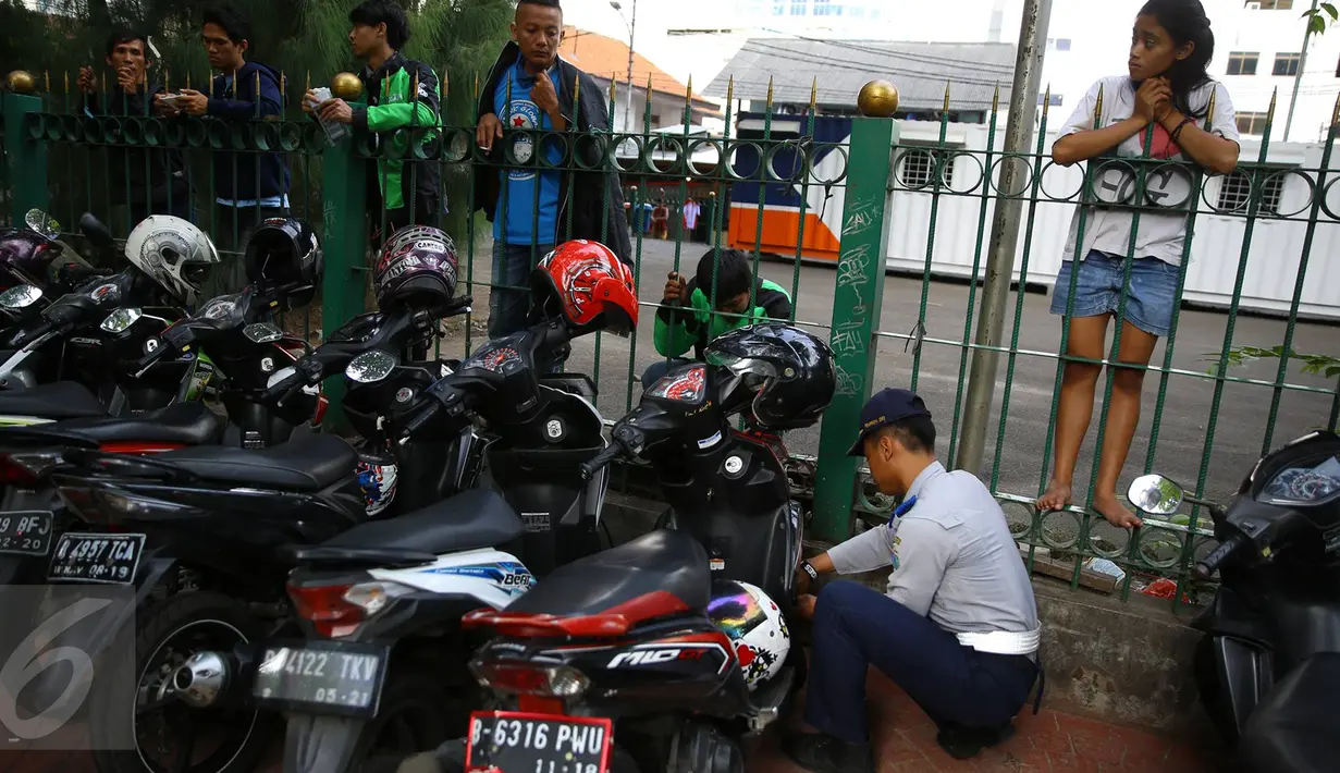 Petugas Dishub mengembosi motor yang parkir di sepanjang trotoar kawasan Kebon Sirih, Jakarta, Rabu (18/1). Puluhan motor diamankan serta digembosi dalam penertiban tersebut karena menutupi jalur pedestrian. (Liputan6.com/Immaniel Antonius)