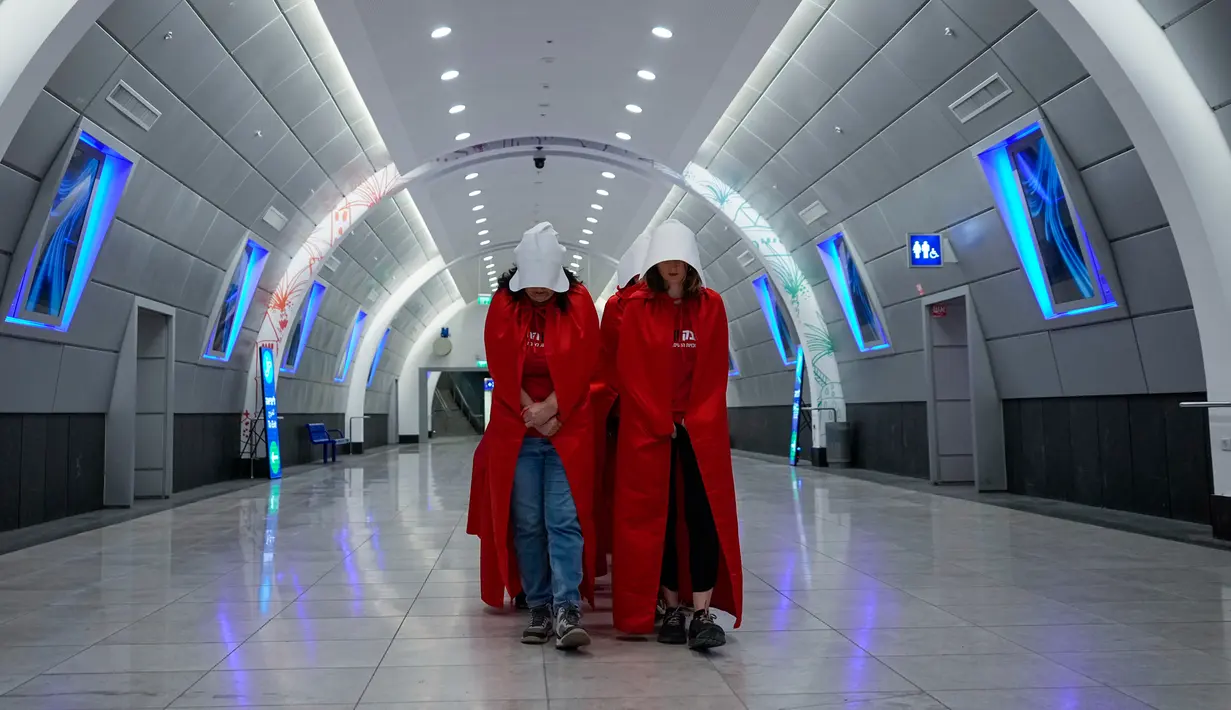 Pengunjuk rasa yang mendukung hak-hak perempuan berpakaian seperti karakter dari serial TV "The Handmaid's Tale" saat melakukan perjalanan untuk memprotes rencana pemerintah baru Perdana Menteri Benjamin Netanyahu untuk merombak sistem peradilan di sebuah stasiun kereta api di Yerusalem, Israel, 1 Maret 2023. Mengacu pada fenomena yang berkembang, harian Inggris The Guardian menggambarkan penampilan para pelayan sebagai salah satu simbol paling kuat dari protes feminis kontemporer. (AP Photo/Ohad Zwigenberg)