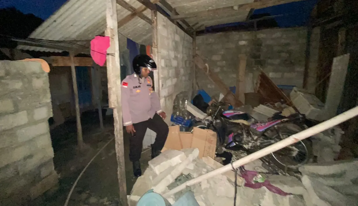 Seorang petugas polisi memeriksa rumah yang rusak setelah gempa melanda kepulauan Tanimbar di Maluku (10/1/2023). Gempa dengan magnitudo (M) 7,6 berdampak pada kerusakan sejumlah rumah warga di daerah itu. (Photo by Handout / BNPB / AFP)