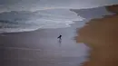 Seorang peselancar berjalan di pinggir pantai menunggu ombak besar saat berselancar di Praia do Norte di Nazare, Portugal (19/11). (Reuters/Rafael Marchante)