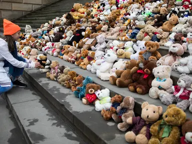 Seorang siswa meletakkan satu boneka beruang atau Teddy Bears di tangga Concert Hall, Berlin, Kamis (15/3). Kelompok bantuan kemanusiaan World Vision melakukan aksi pengumpulan 740 boneka beruang. (AFP PHOTO/Odd ANDERSEN)