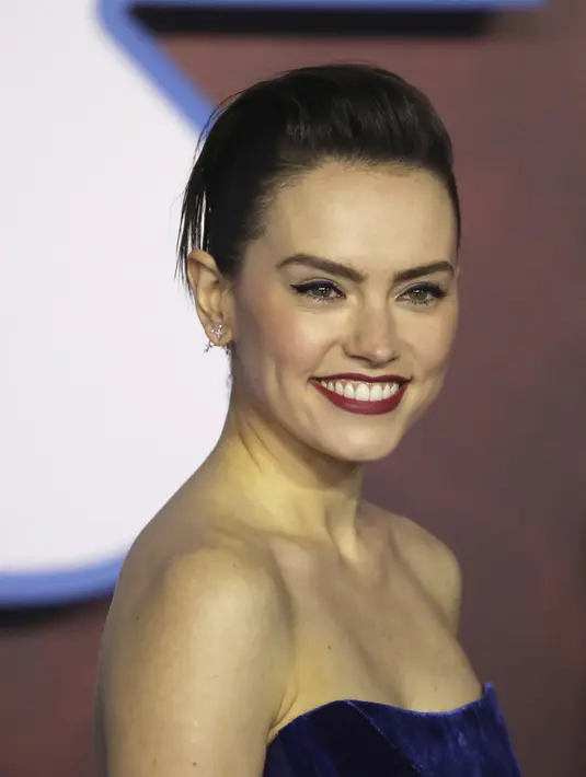 Aktris Inggris Daisy Ridley tersenyum saat tiba menghadiri pemutaran perdana film Star Wars: The Rise Of Skywalker" di London (18/12/2019). Daisy Ridley mengenakan sepasang stiletto satin hitam dan perhiasan cincin perak dan permata yang tebal. (AP Photo/Vianney Le Caer)