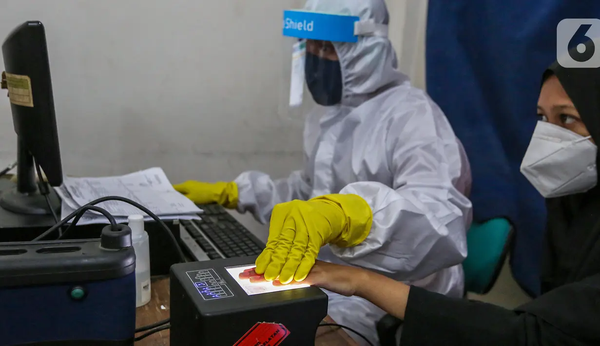 Petugas Dukcapil lengkap dengan APD memindai sidik jari KTP Elektronik di Kecamatan Pamulang, Tangerang Selatan, Senin (15/6/2020) Dukcapil Tangsel membuka layanan rekaman E-KTP jelang Pilkada dengan menerapkan ketentuan New Normal guna mencegah penyebaran Virus Covid-19. (Liputan6.com/Fery Pradolo)