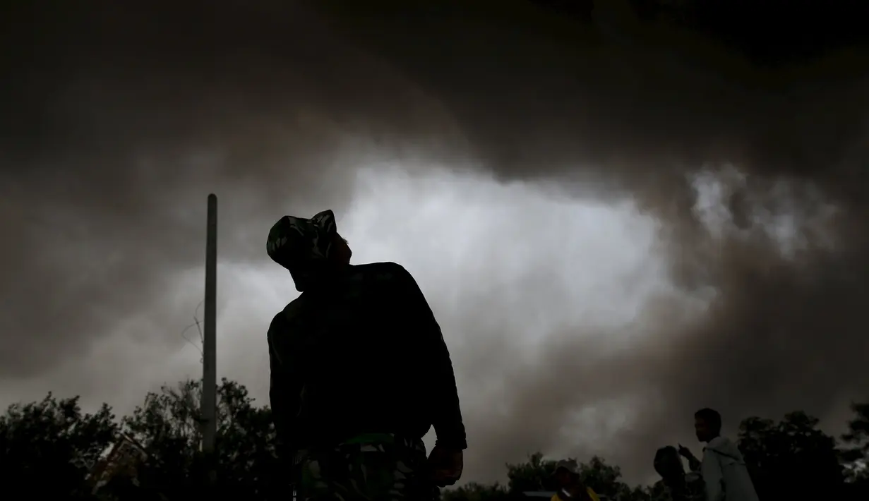Seorang tentara menyaksikan Gunung Sinabung melontarkan awan panasnya di Desa Tiga Serangkai, Karo, Sumatera Utara, Rabu (24/6/2015). Sekitar 10.000 jiwa warga yang tinggal di kaki Gunung Sinabung, kini berada di posko pengungsian. (REUTERS/Beawiharta)