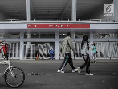 Warga berolahraga melintasi pintu masuk zona 9 Stadion Utama Gelora Bung Karno yang rusak pada Final Piala Presiden 2018, Jakarta, Minggu (18/2). Kerusakan disebabkan suporter salah satu tim sepakbola yang merangsek masuk. (Liputan6.com/Faizal Fanani)