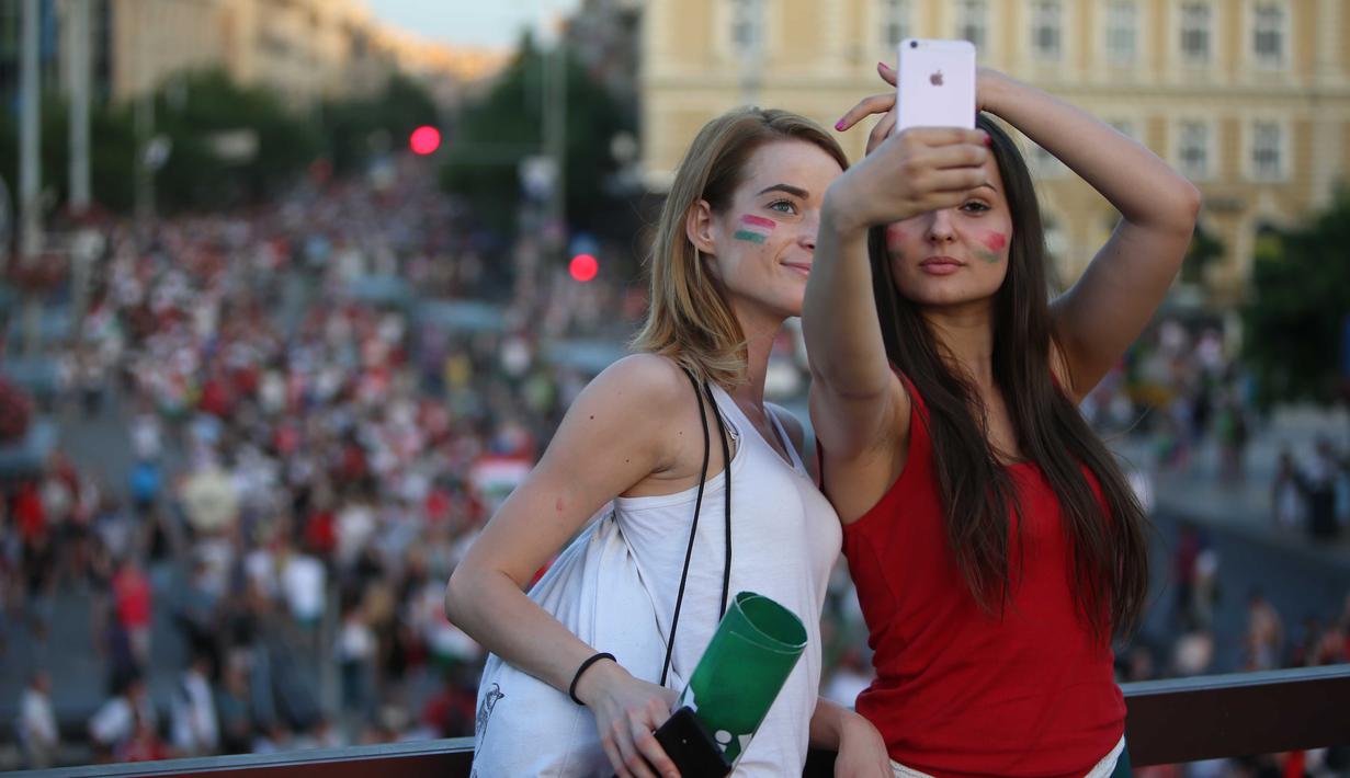 Dua fans cantik asal Hungaria merayakan kemenangan timnya dengan berfoto selfie diatas gedung usai laga grup F Euro Cup 2016 antara Hungaria vs Portugal di Athletic Stadium, Margit Sziget, Budapest, (22/6/2016). (AFP/Ferenc Isza)