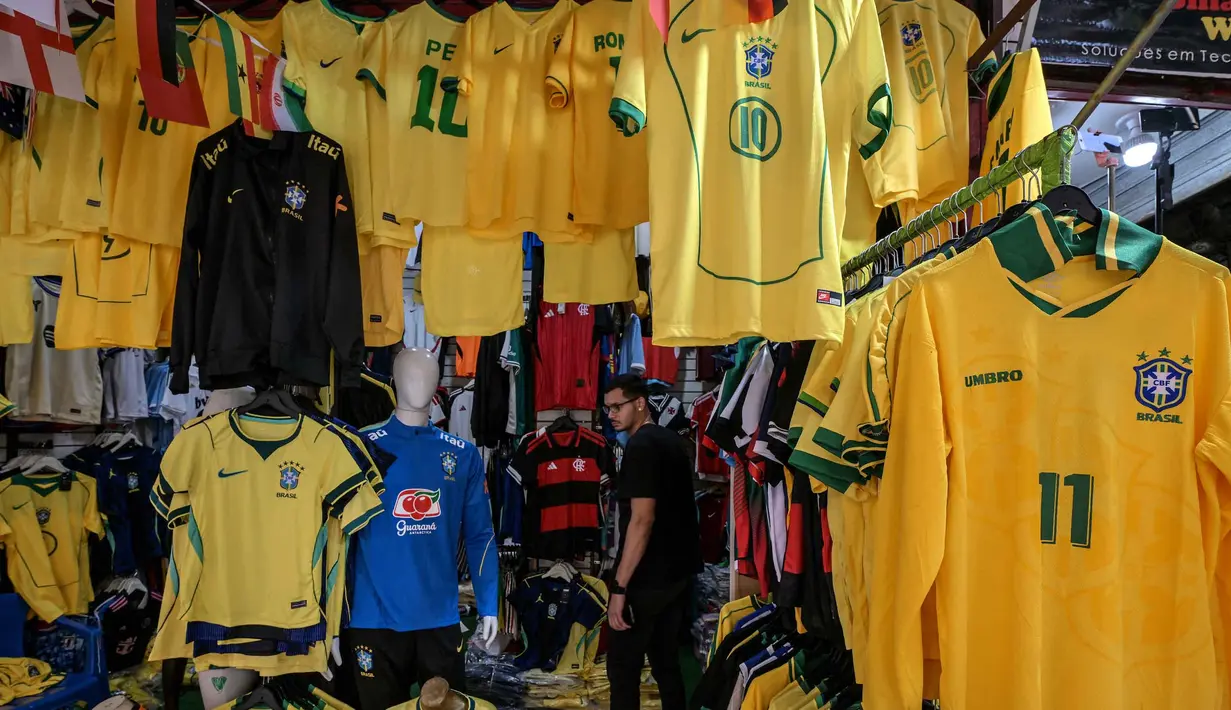 Seorang pria melihat kaus tim sepak bola nasional Brasil yang dipajang di pasar Saara, Rio de Janeiro, Brasil, pada Selasa 9 Juni 2026, menjelang turnamen Piala Dunia FIFA 2026. (Nelson ALMEIDA/AFP)