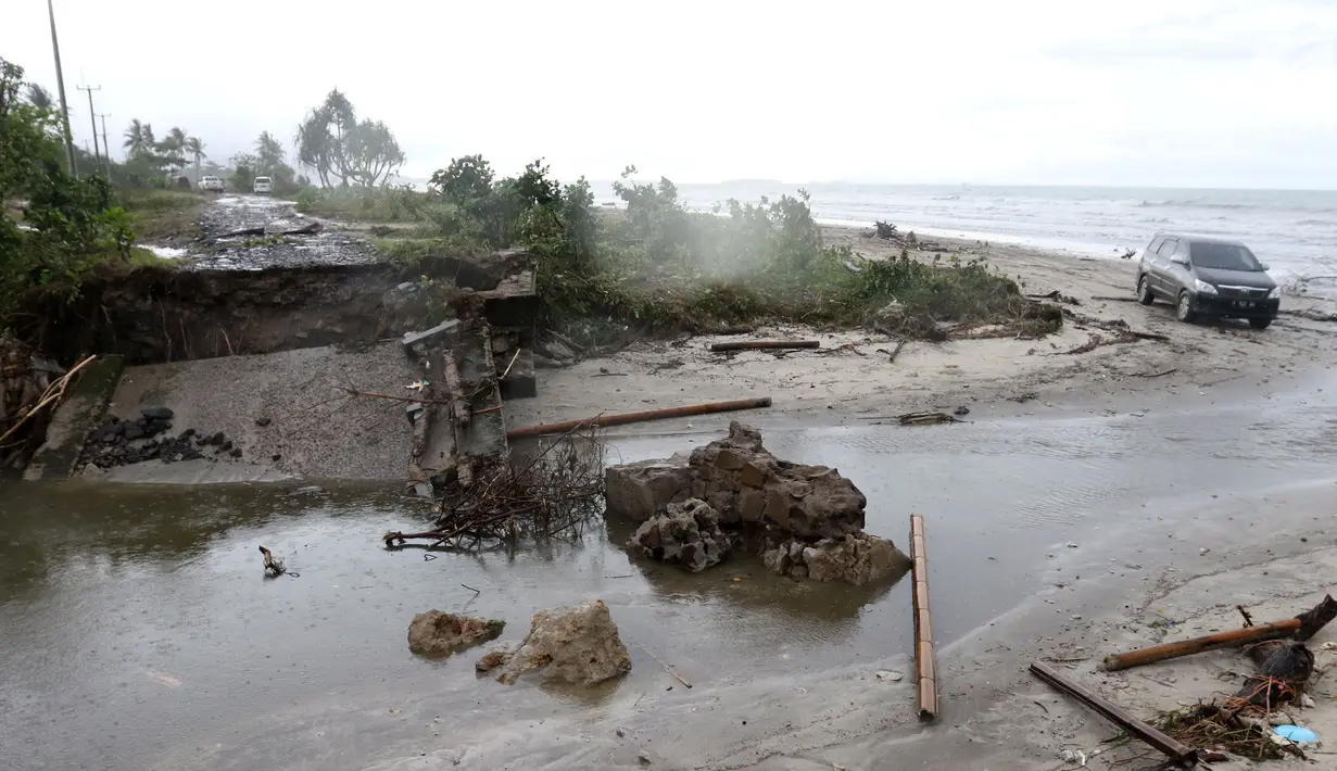 Sebuah mobil melintasi pantai karena jembatan di jalur alternatif Sumur, Banten, ambruk, Senin (24/12). Jembatan penghubung ambruk diterjang gelombang Tsunami Selat Sunda. (Liputan6.com/Angga Yuniar)